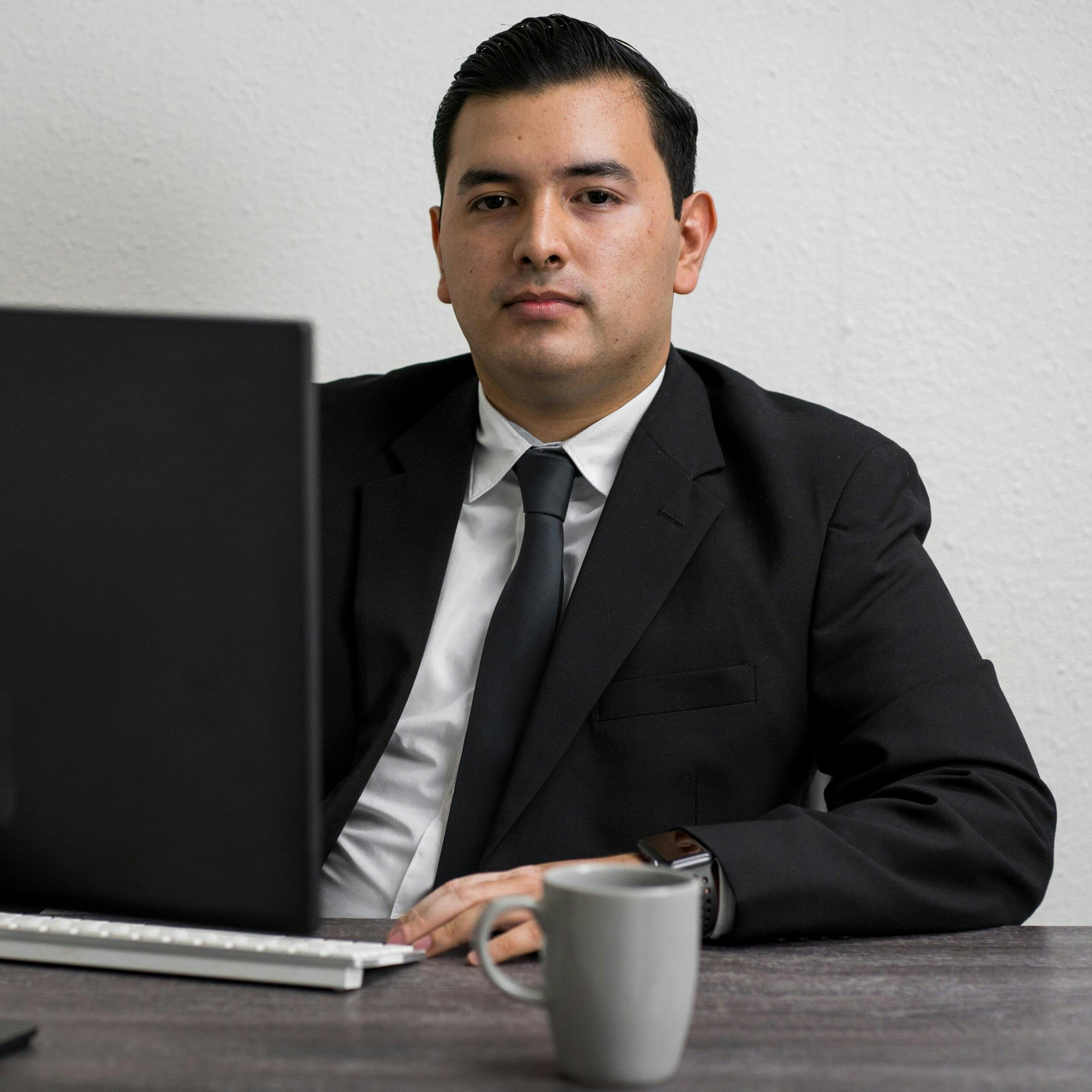 Man in suit behind a laptop