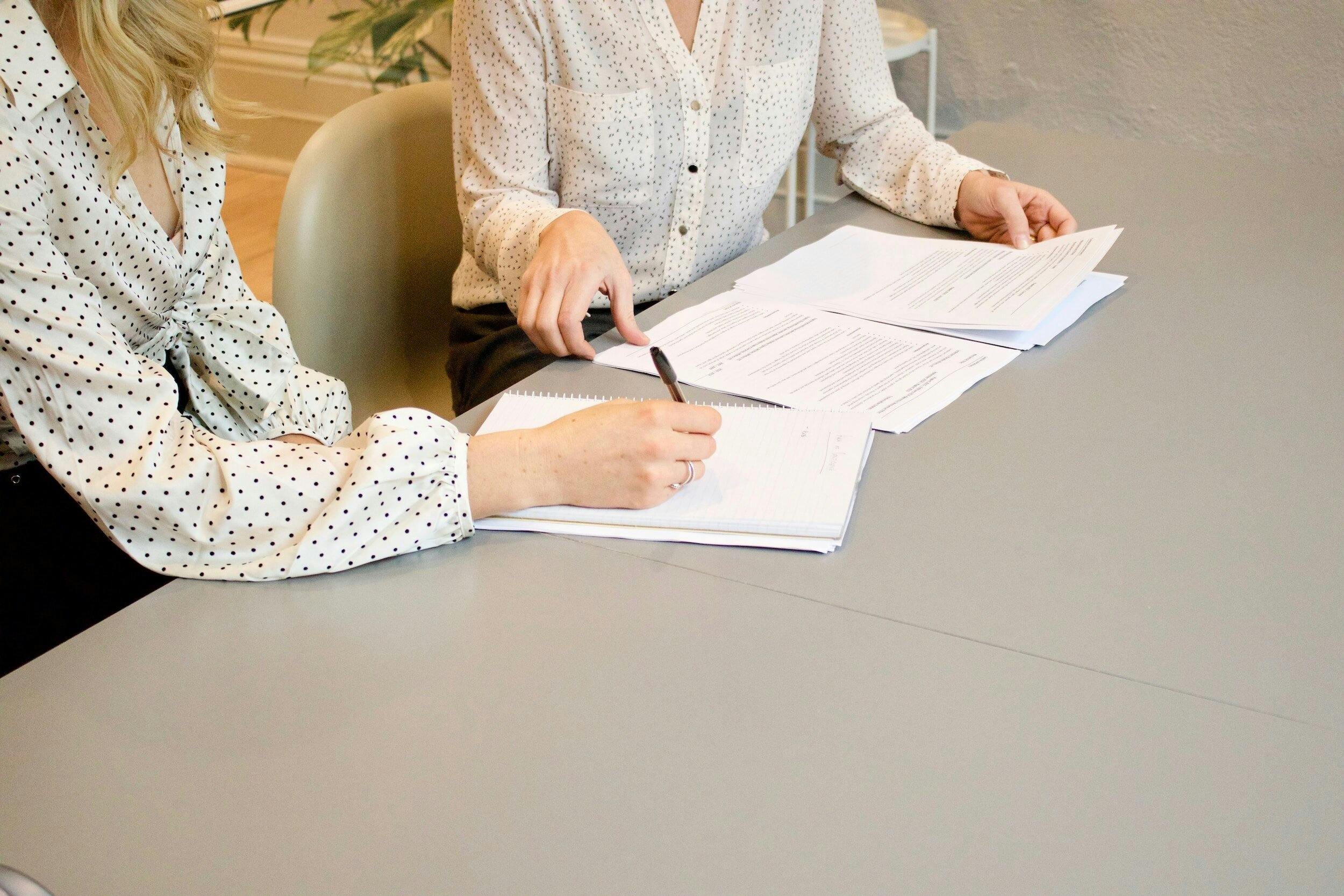 Two Woman writing on documents